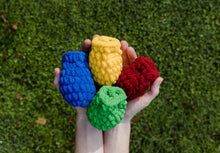 Load image into Gallery viewer, Hands holding 4 EcoSplat reusable water balloons over the grass. The water balloons are red  green, blue, yellow).
